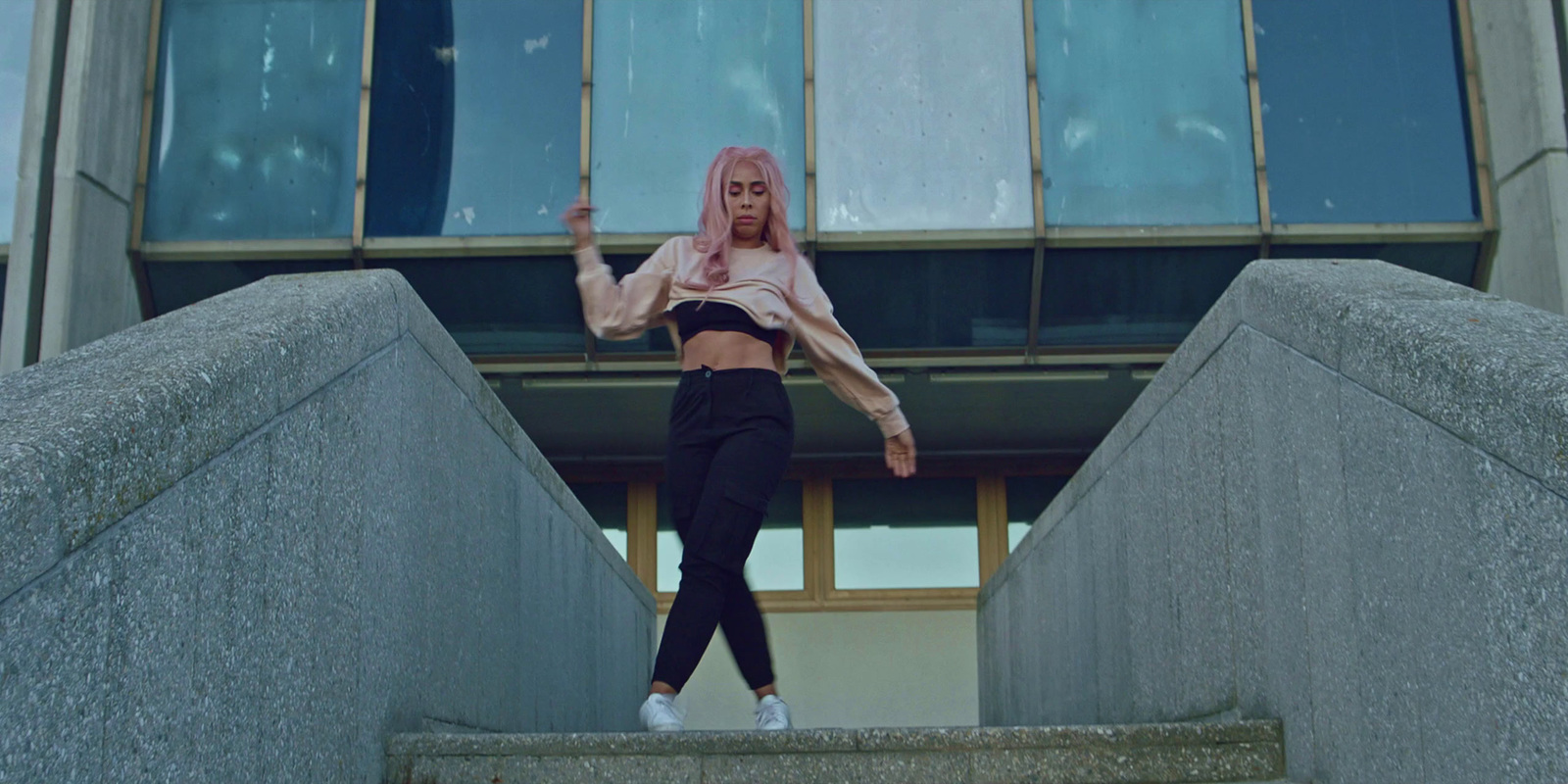 a woman with pink hair standing on steps