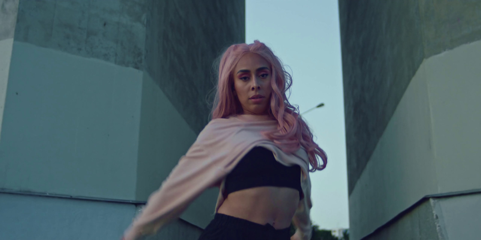 a woman with pink hair is standing in front of a building