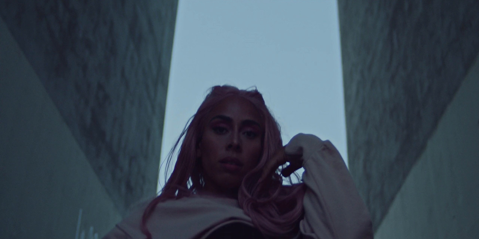 a woman with pink hair standing in a hallway