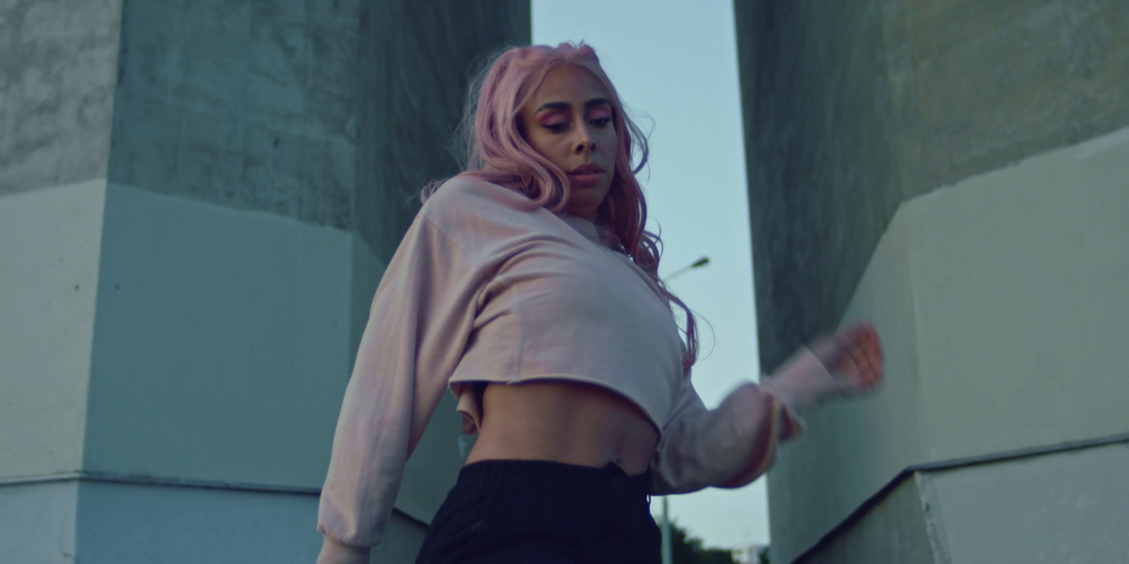 a woman with pink hair standing in front of a wall