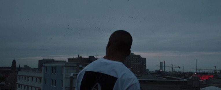 a man standing on top of a roof next to a tall building