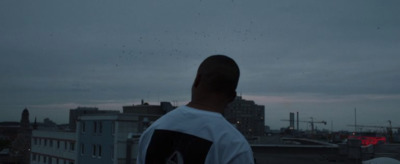 a man standing on top of a roof next to a tall building