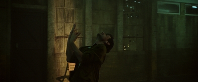 a man in a dark room reaching up into the air