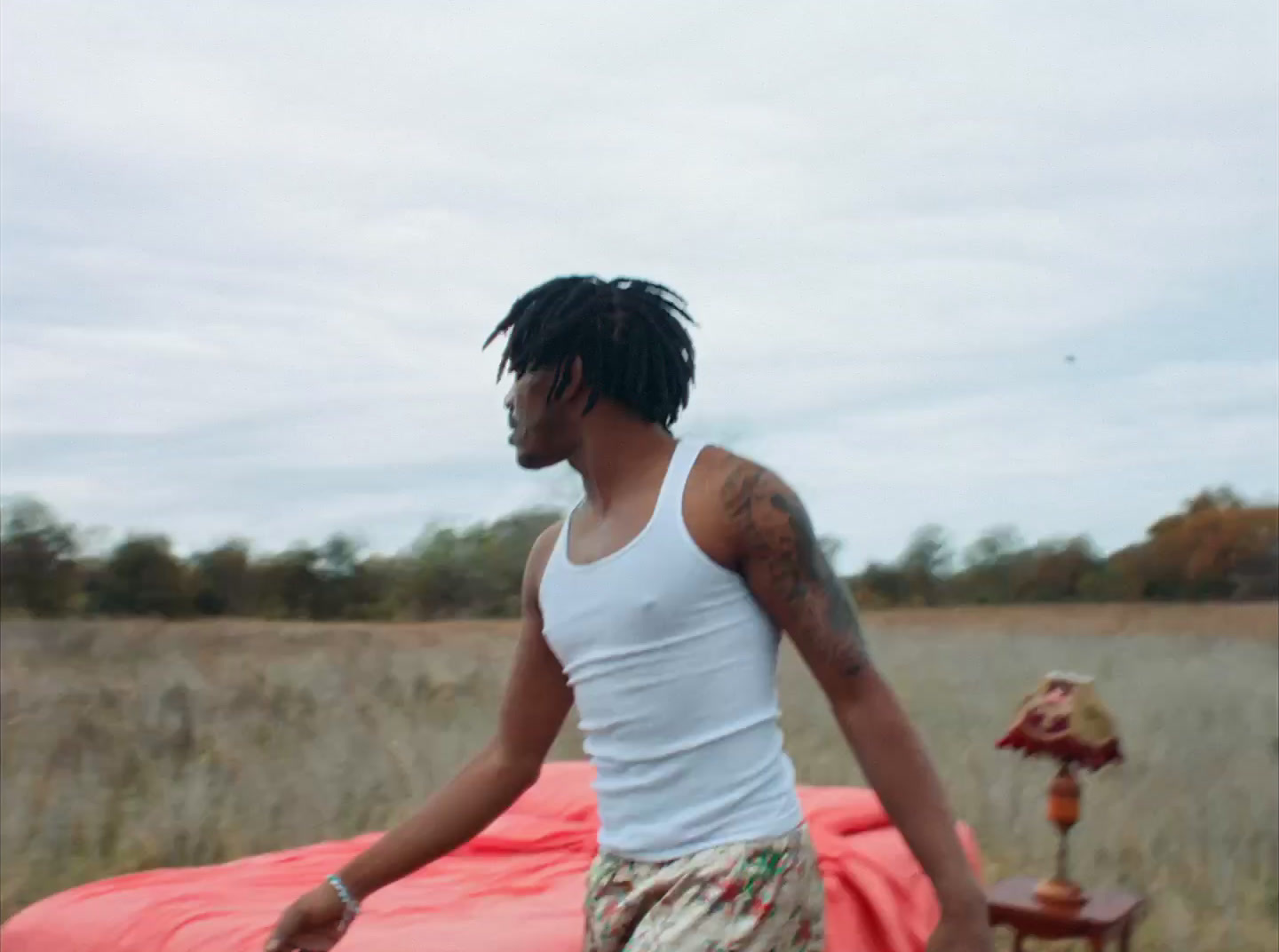 a man with dreadlocks walking in a field