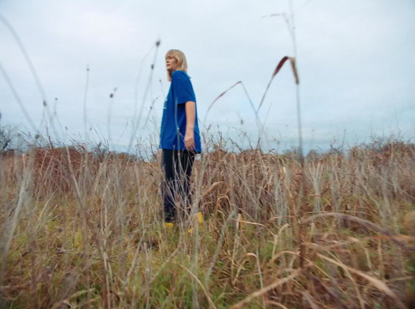 a woman standing in a field of tall grass