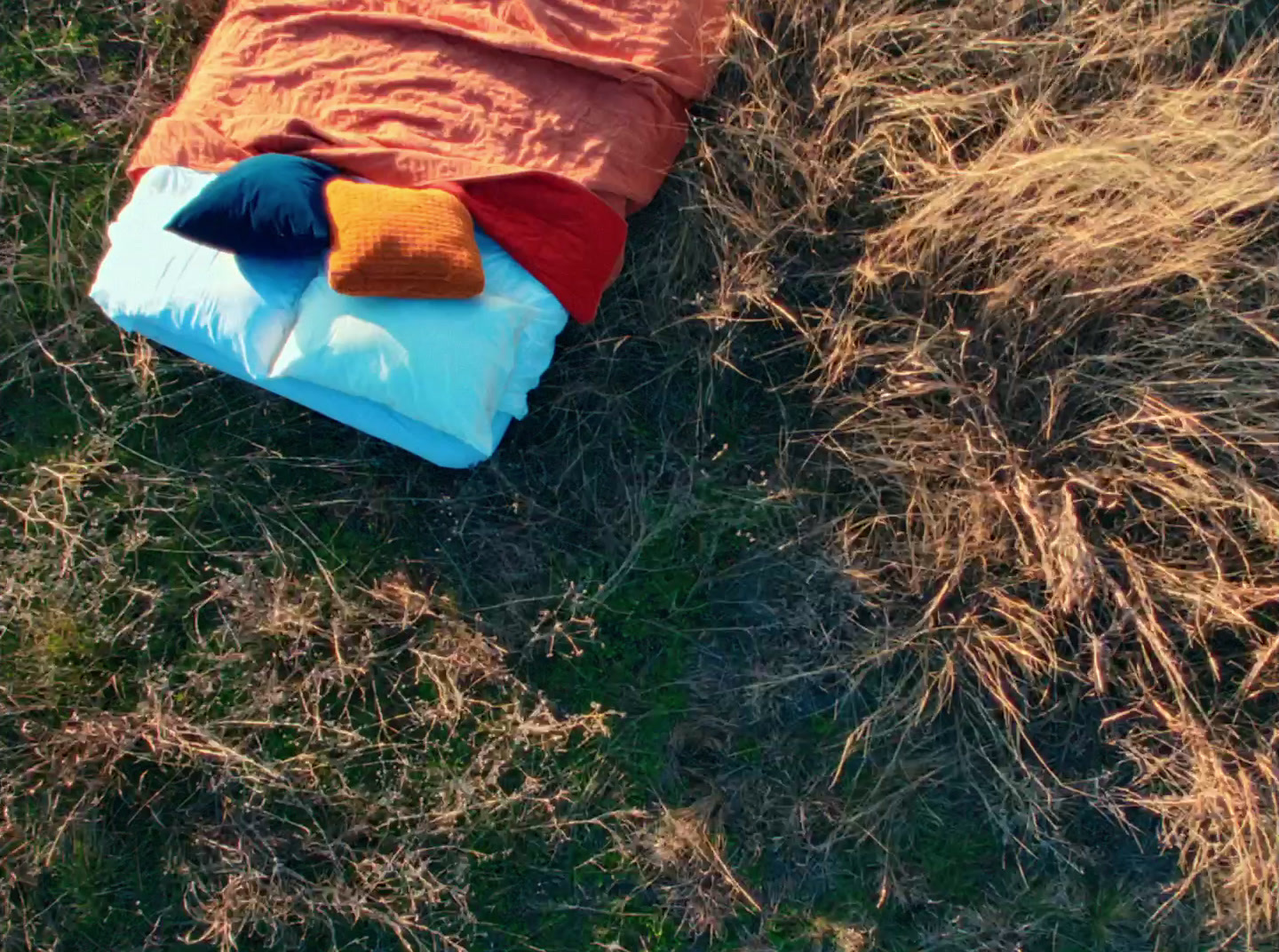 a sleeping bag is on the ground in the grass