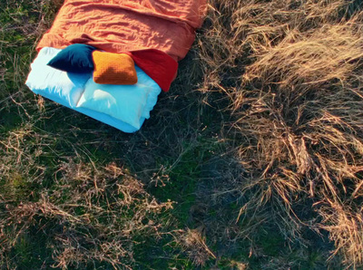 a sleeping bag is on the ground in the grass