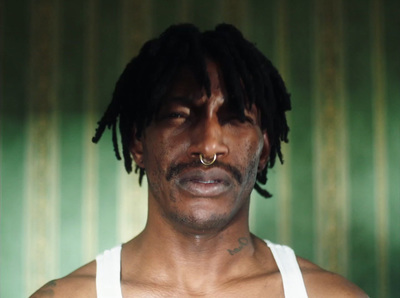 a man with dreadlocks wearing a white tank top