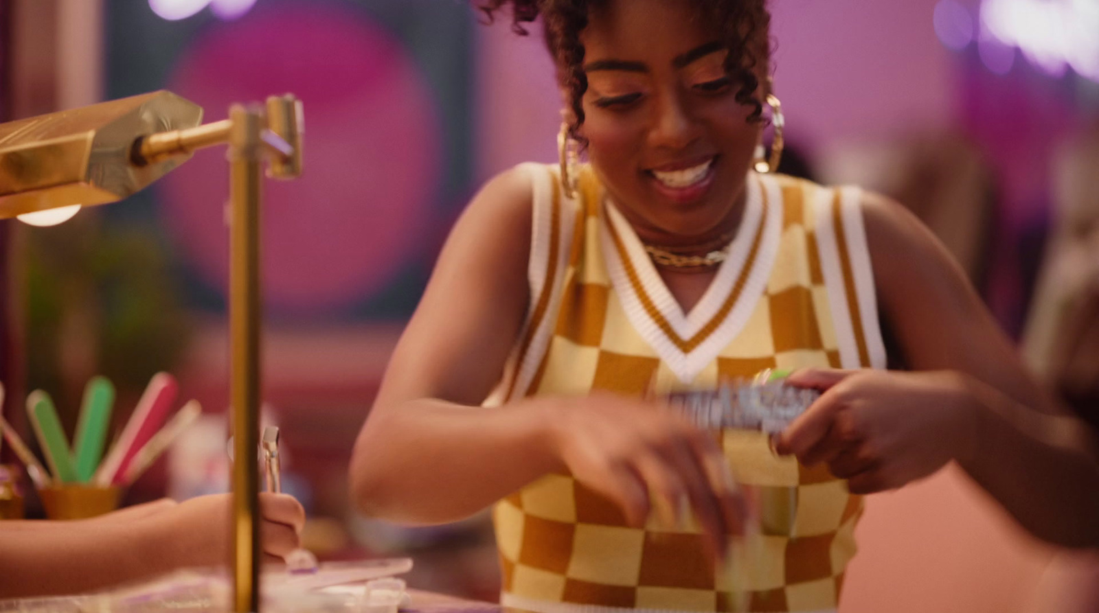 a woman in a yellow and checkered shirt is cutting a piece of cake