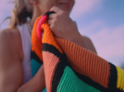 a woman is holding a colorful sweater over her shoulder