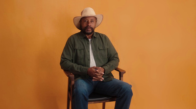 a man sitting in a chair wearing a cowboy hat