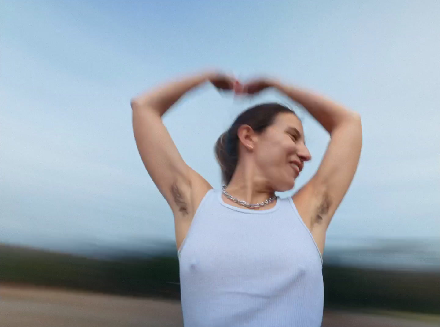 a woman in a white tank top holding her hands up in the air