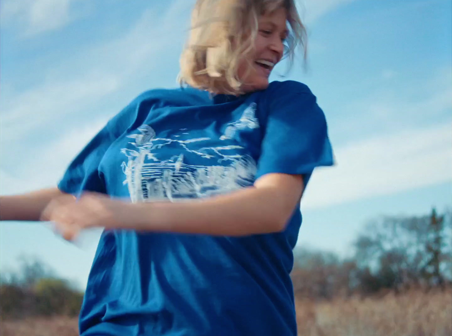 a woman in a blue shirt is throwing a frisbee