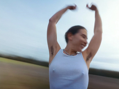 a woman in a white tank top holding her arms in the air