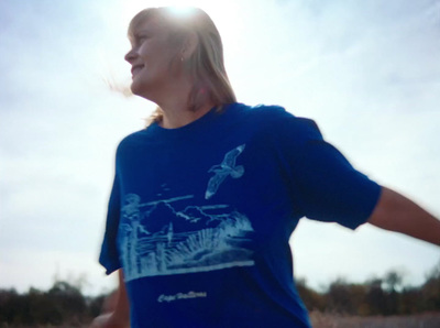 a woman in a blue shirt is throwing a frisbee