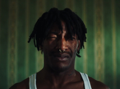 a man with dreadlocks wearing a white tank top