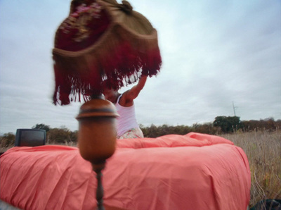 a woman sitting on top of a bed in a field