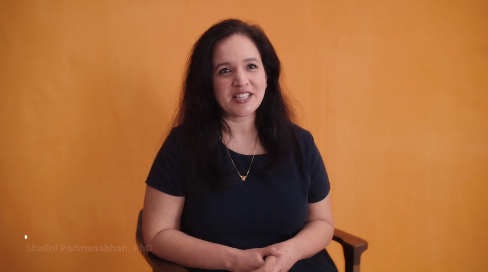 a woman sitting in a chair in front of a yellow wall