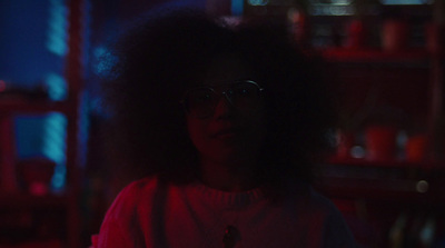 a woman with glasses standing in a dark room