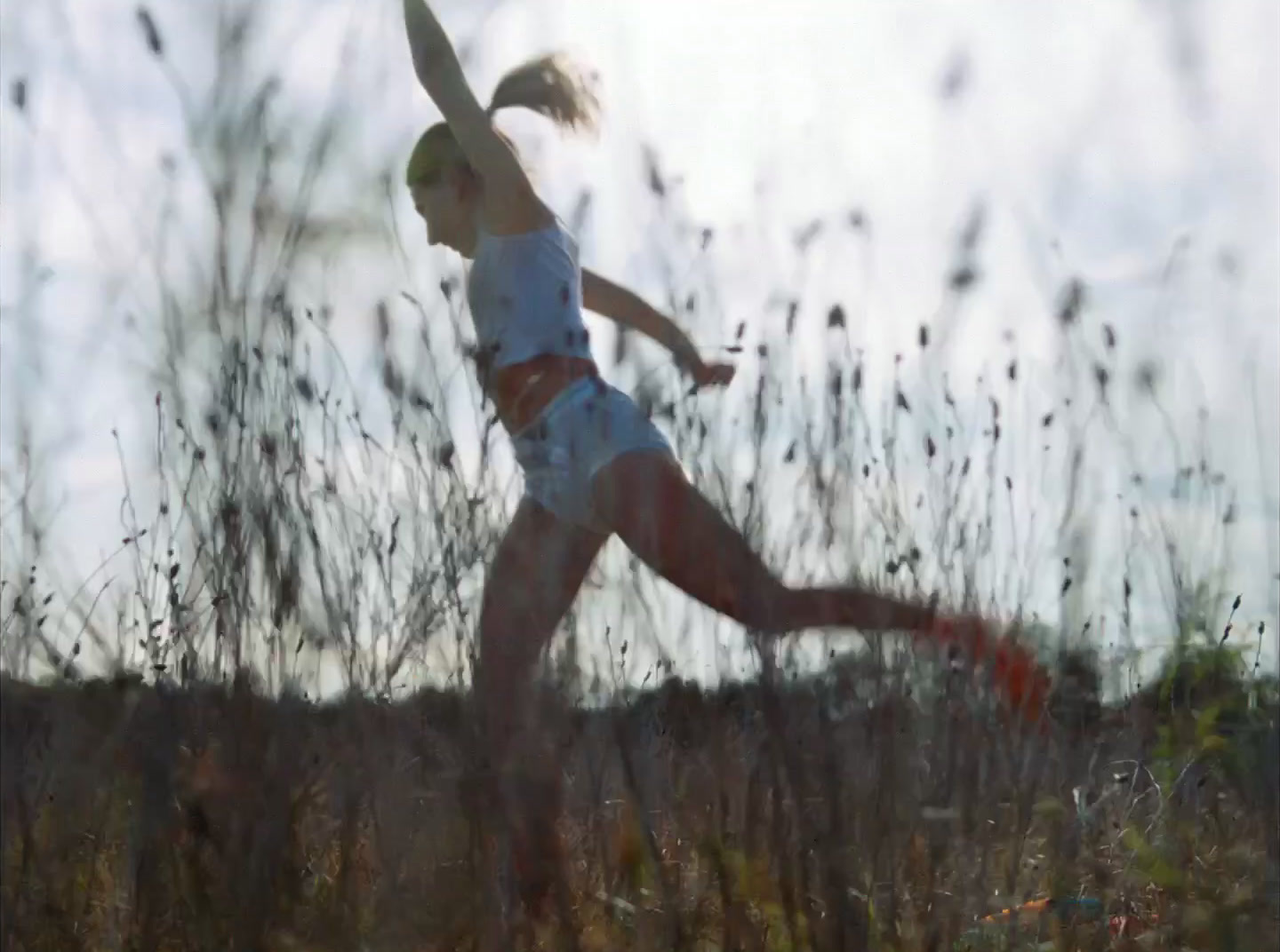 a woman running through a field of tall grass