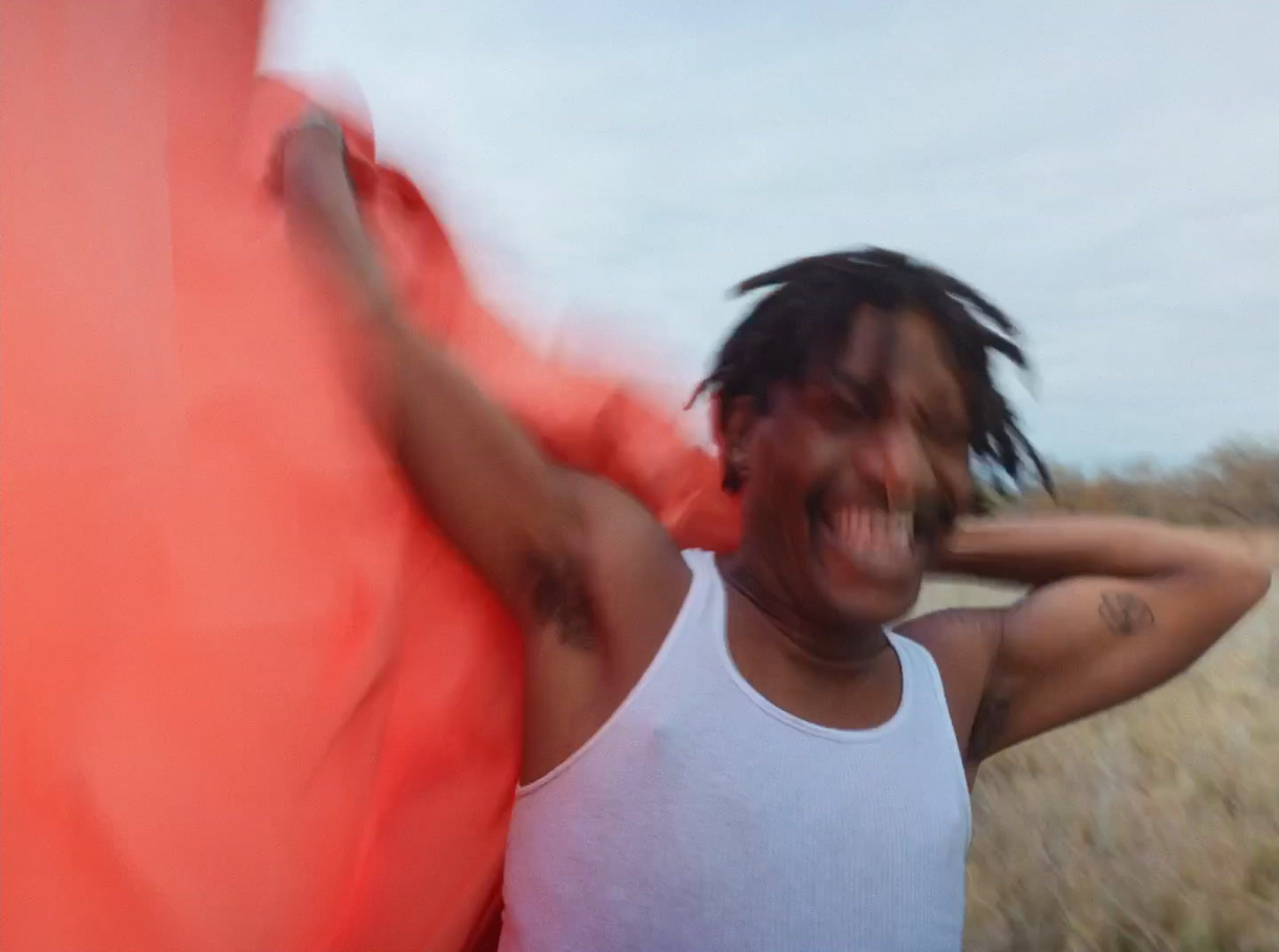 a man with dreadlocks and a white tank top