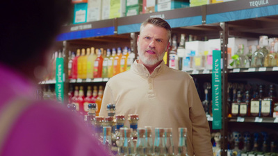 a man standing in front of a shelf of liquor