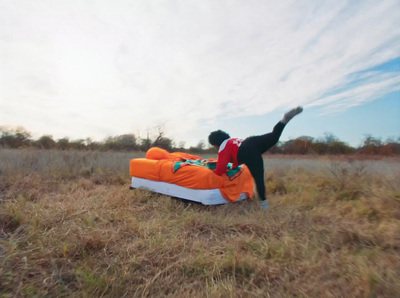 a man is doing a handstand on a bed in a field