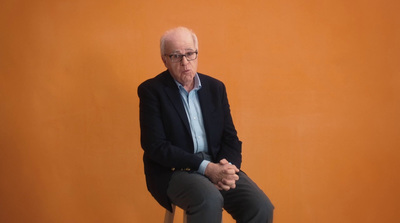 a man sitting on a stool in front of an orange wall