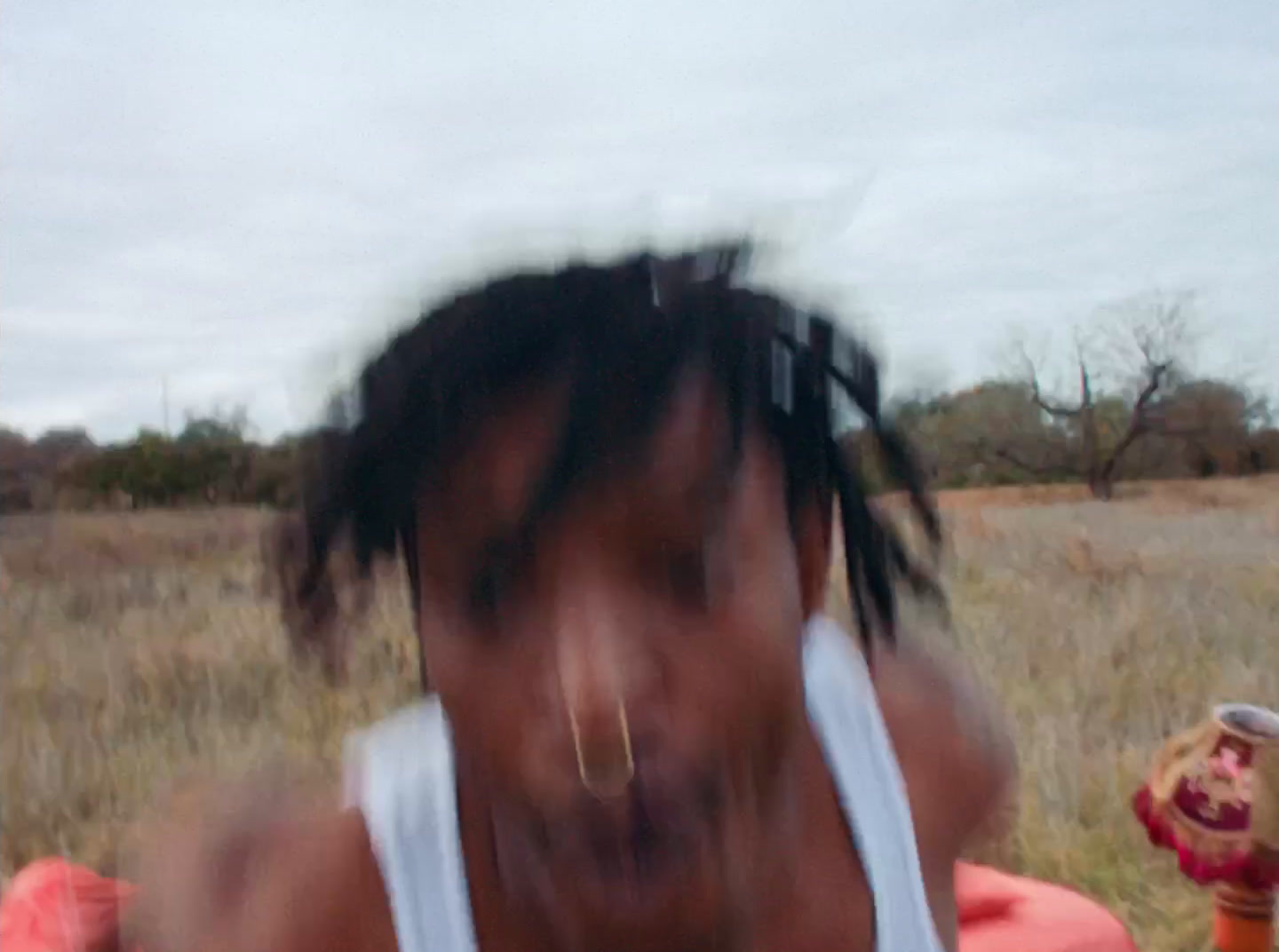 a man with dreadlocks standing in a field