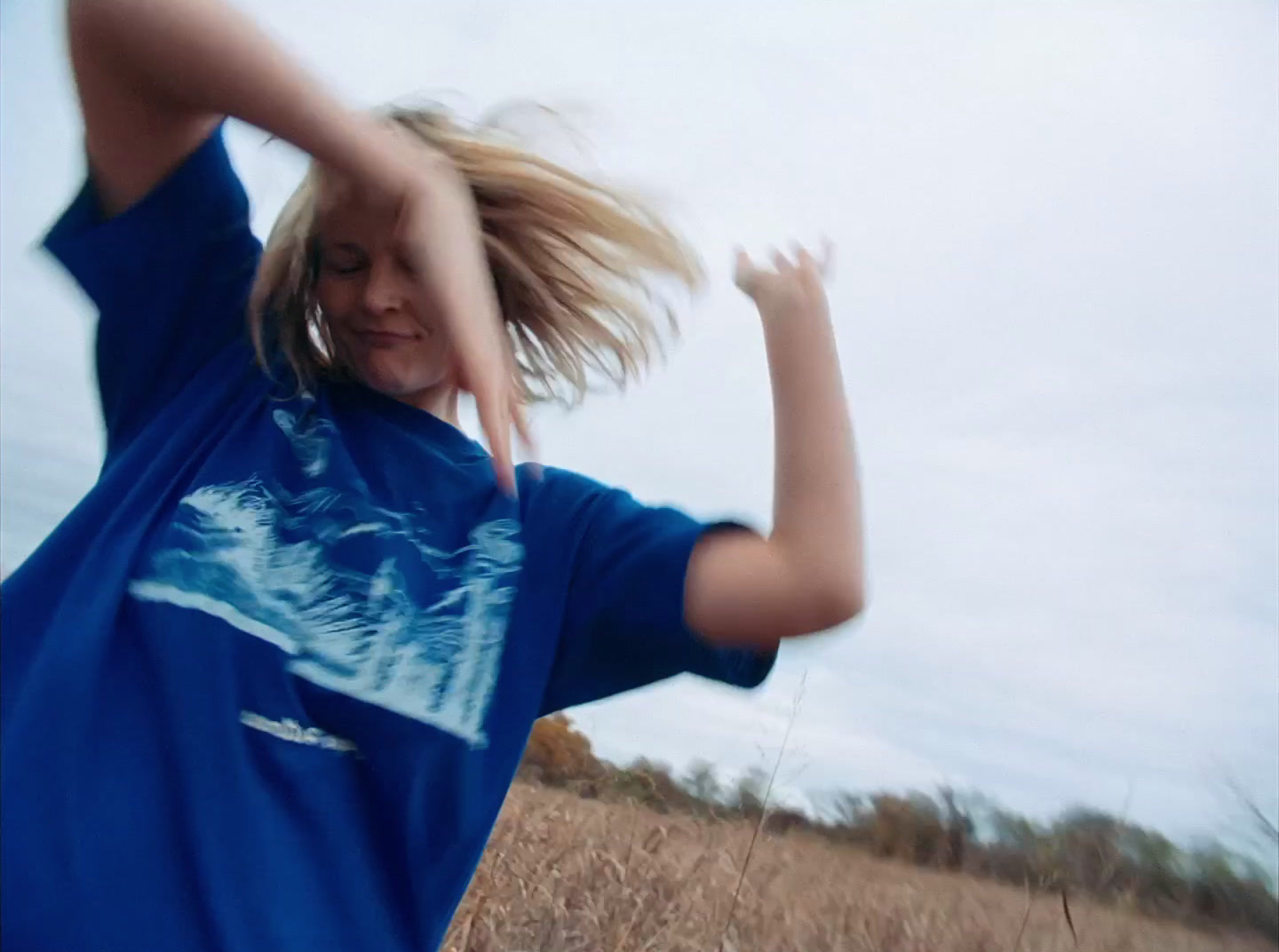 a girl in a blue shirt throwing a frisbee