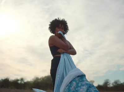 a woman standing on a beach holding a blue bag