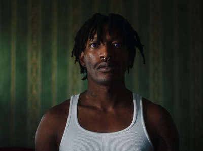 a man with dreadlocks standing in a dark room