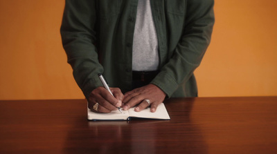 a person writing on a piece of paper with a pen