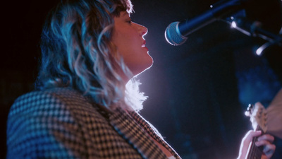 a woman singing into a microphone while holding a guitar