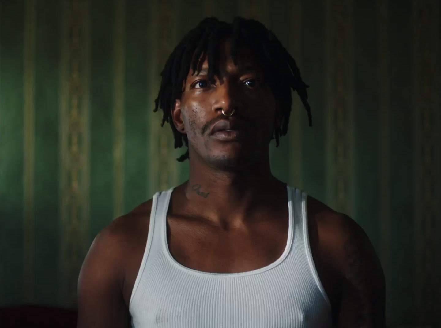 a man with dreadlocks standing in a dark room