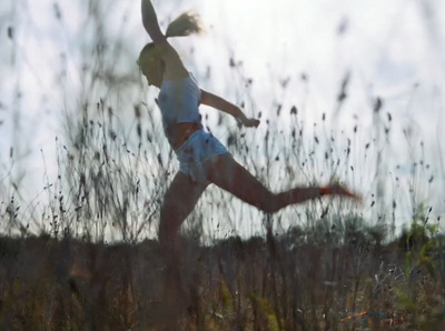 a woman running through a field of tall grass