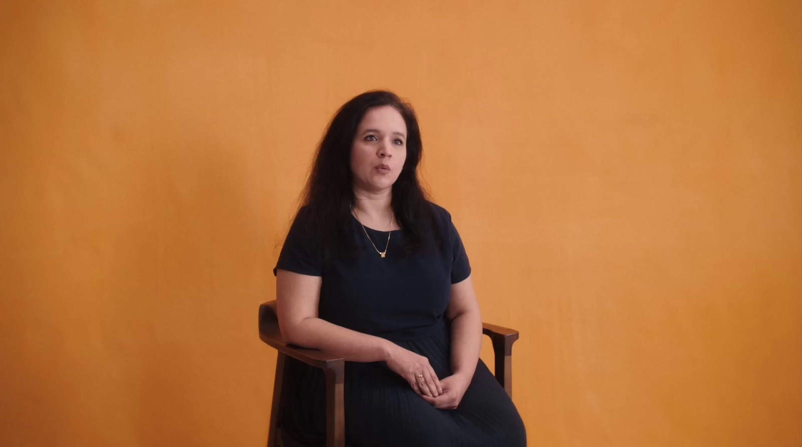 a woman sitting in a chair in front of a yellow wall