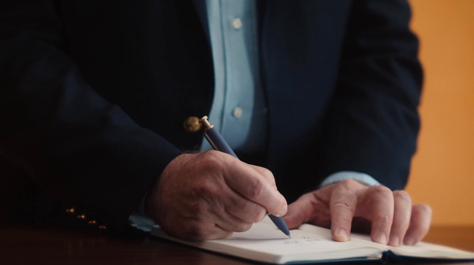 a man writing on a notebook with a pen