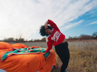 a woman standing next to a bed in a field