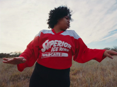 a woman standing in a field with her arms outstretched