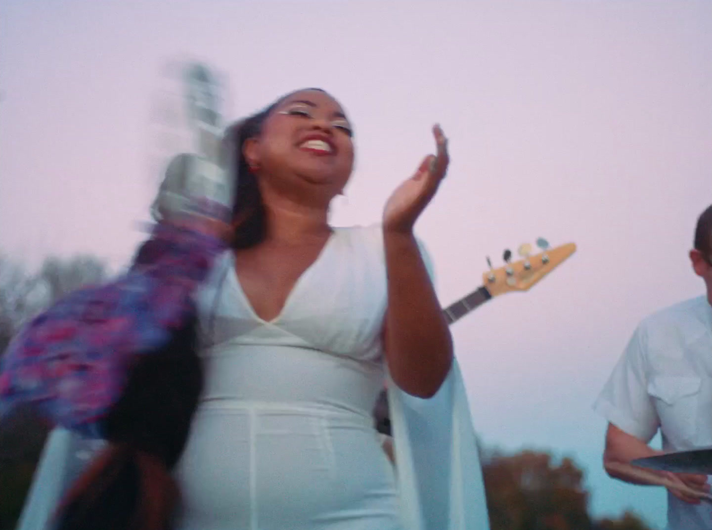 a woman in a white dress holding a guitar