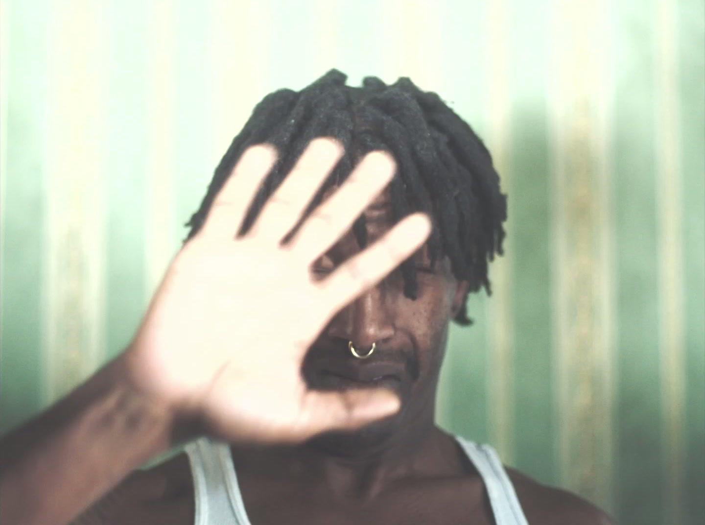 a man with dreadlocks holding his hand up to his face