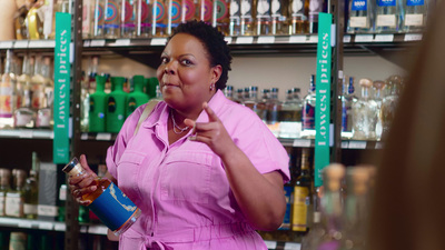 a woman standing in a store holding a bottle