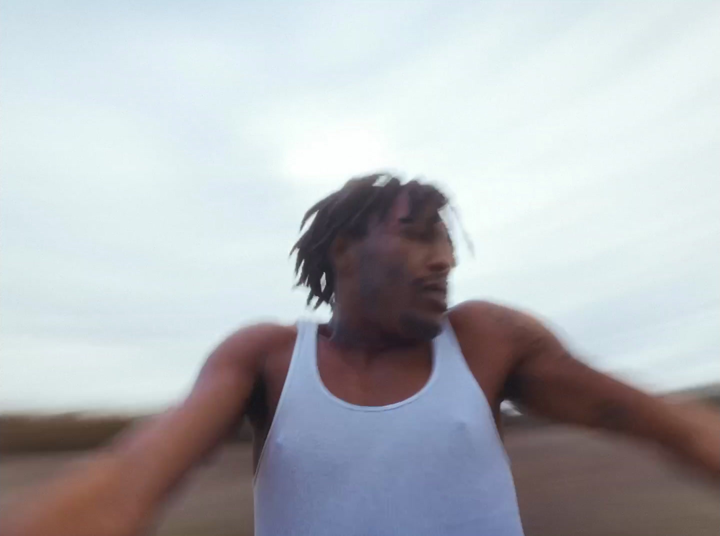 a man in a white tank top holding a white frisbee