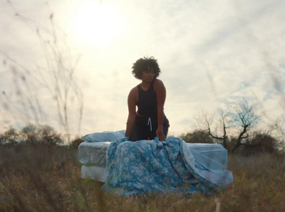 a woman standing on top of a bed in a field