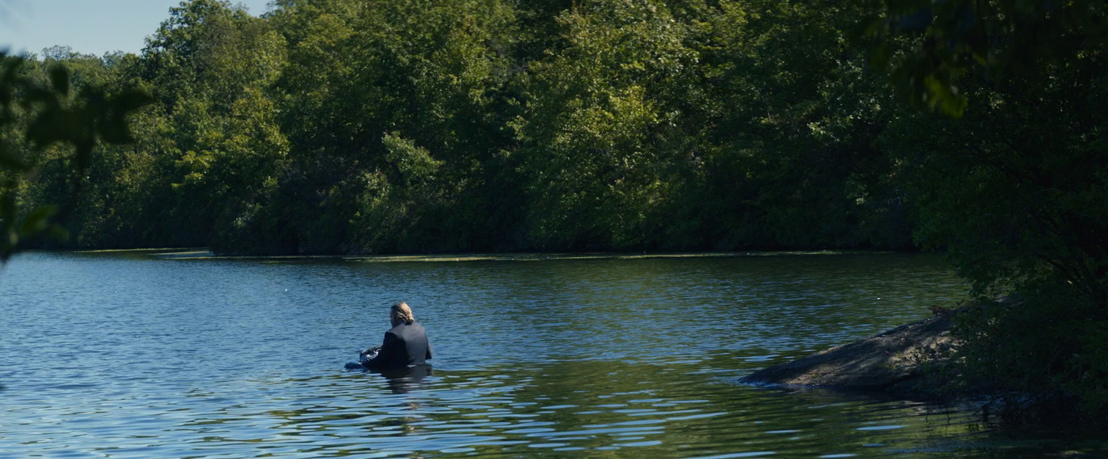 a person in a body of water surrounded by trees