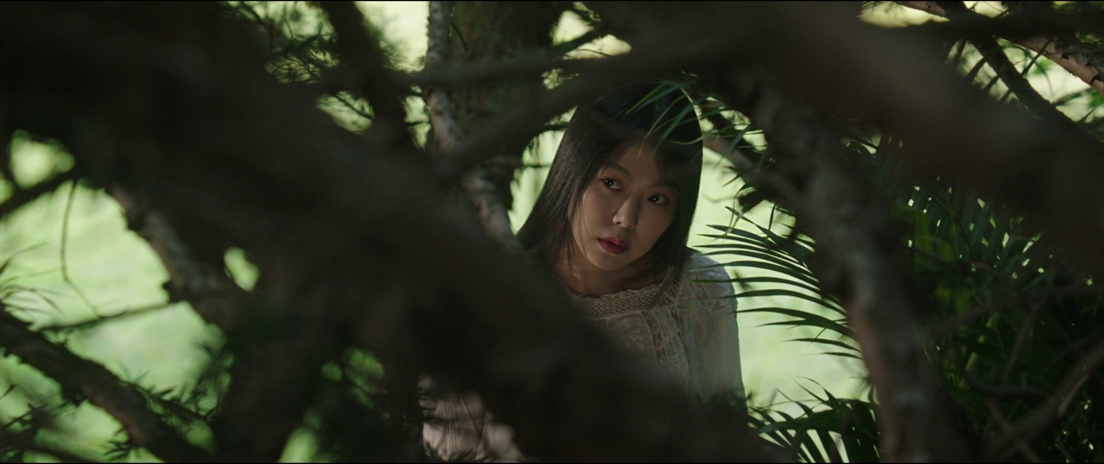 a woman standing under a tree looking at the camera