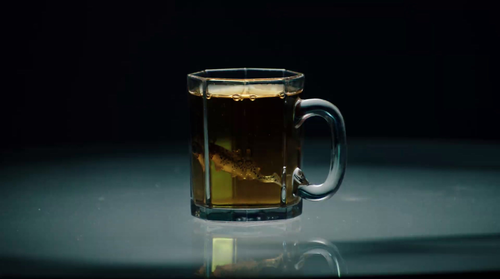 a glass mug of tea on a reflective surface