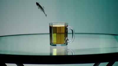 a fish is flying over a glass of tea