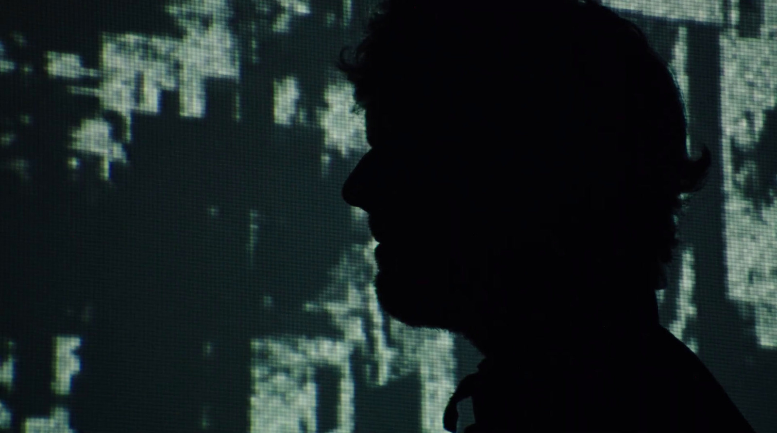 a silhouette of a man in front of a screen